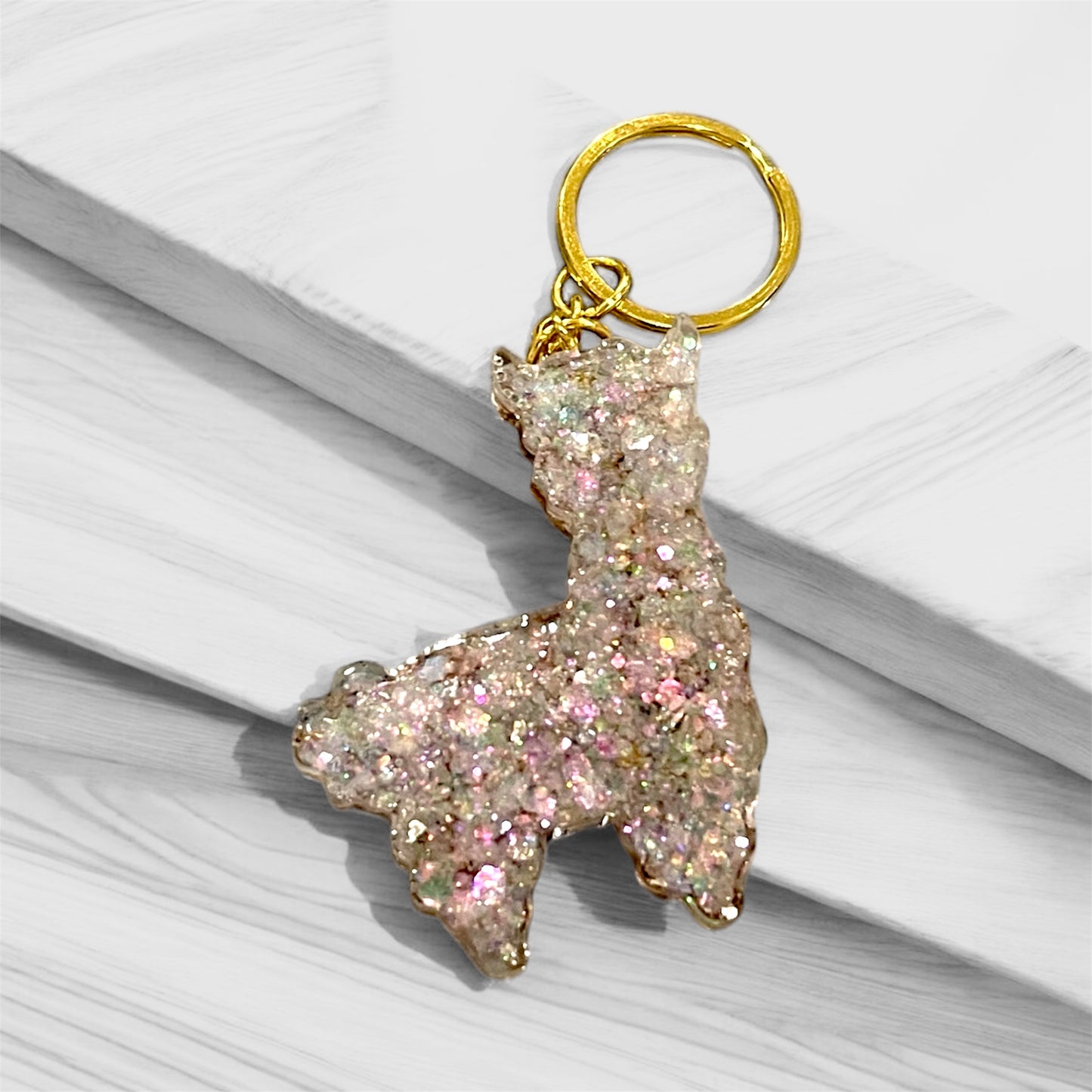 Handmade llama resin keychain with delicate pink and iridescent glitter, featuring gold hardware and whimsical design